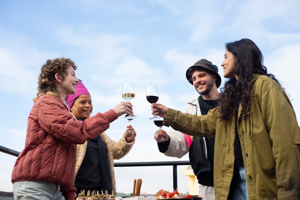 A group of friends celebrating with wine outdoors in Portugal under a clear blue sky.